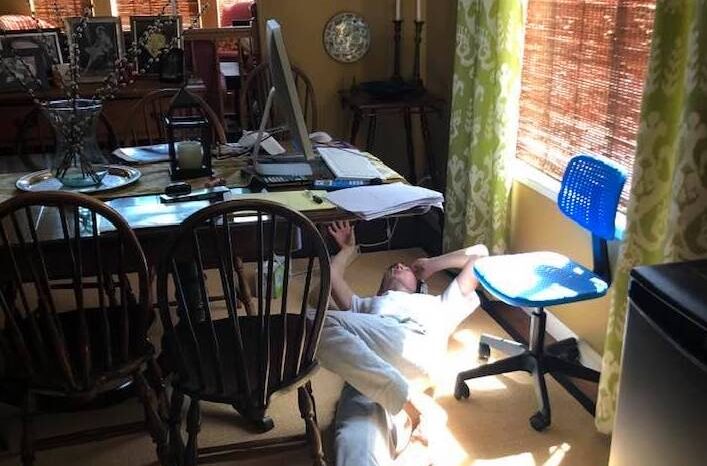 frustrated teenage student lying on ground near schoolwork